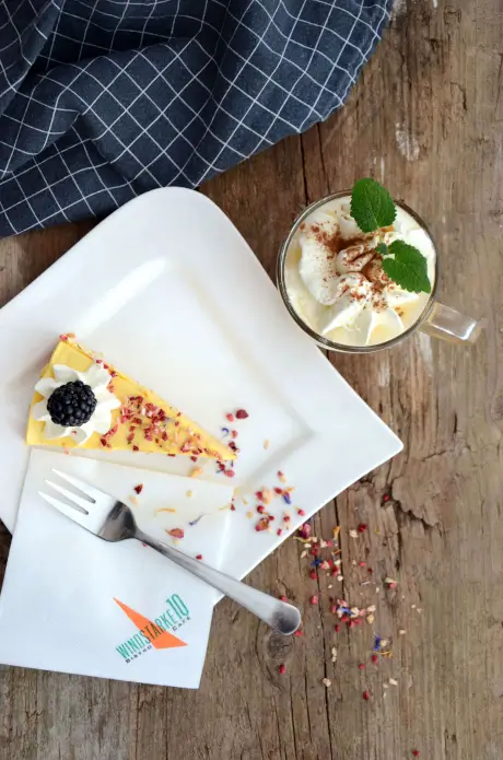 Ein Stück leckere Torte mit Sahne und Beeren, serviert mit einem Getränk in einer Glaskaraffe.